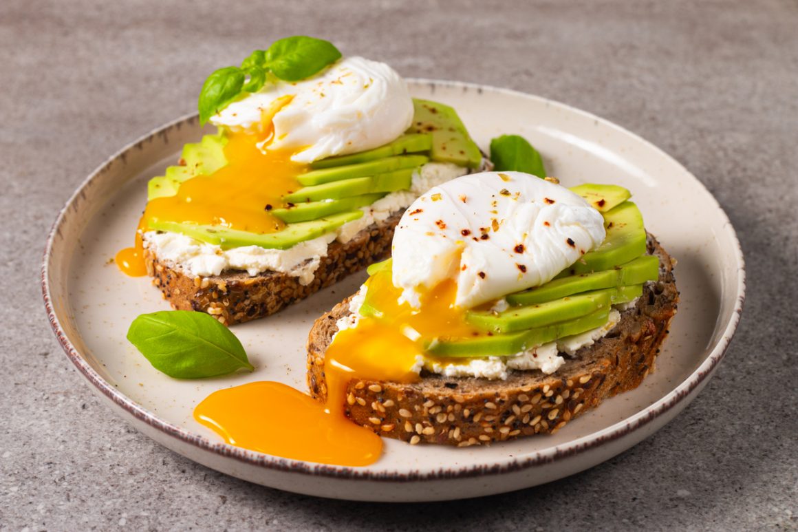Toast with avocado, soft cream cheese, rye bread and poached Egg. Wholemeal open sandwich for healthy breakfast concept