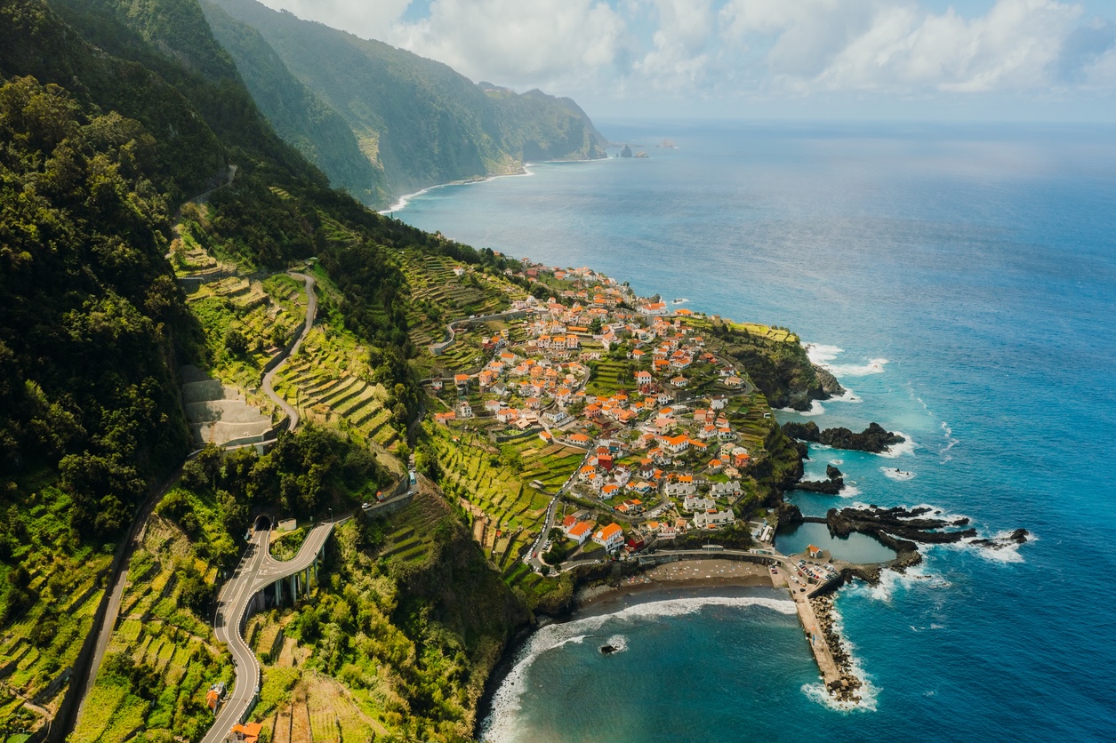 Aerial View of Coastal Road to Town Surrounded by Ocean and Mountains