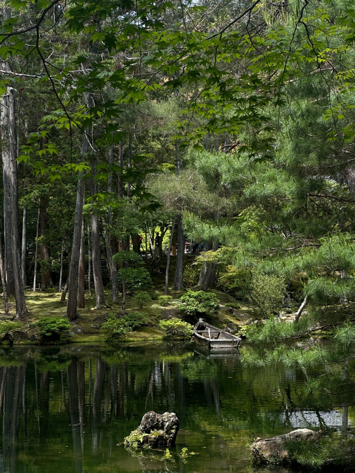 Traditional Japanese garden with a wooden boat beside a peaceful pond