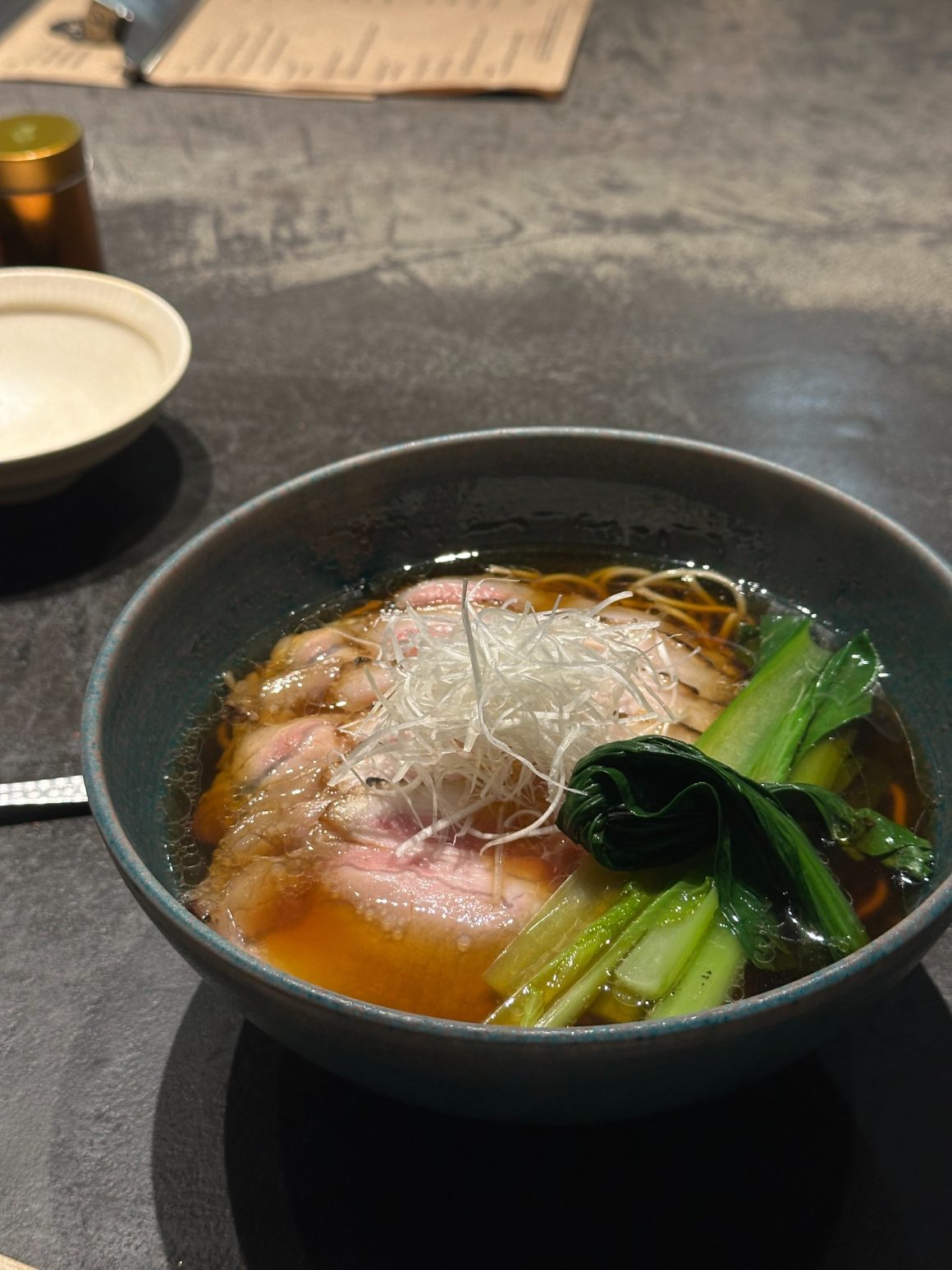 Bowl of Kyoto ramen topped with sliced duck and green onions