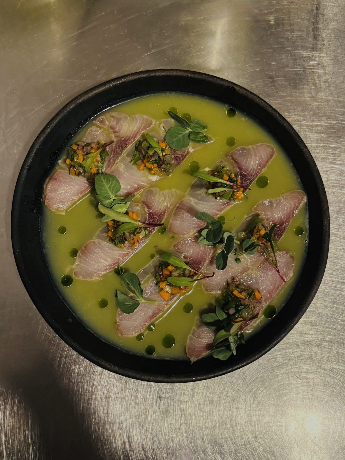Canopia dish with green sauce, black garnish and edible flowers