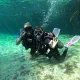Two scuba divers posing underwater in a clear cenote near Tulum, Mexico, making the OK hand signal during a dive.