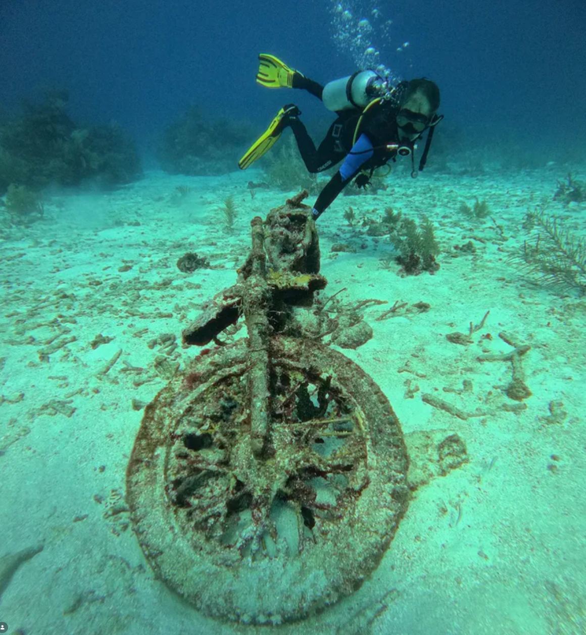 A diver investigates a motorcycle resting on the seabed during a scuba diving excursion off Mexico’s Caribbean coast.