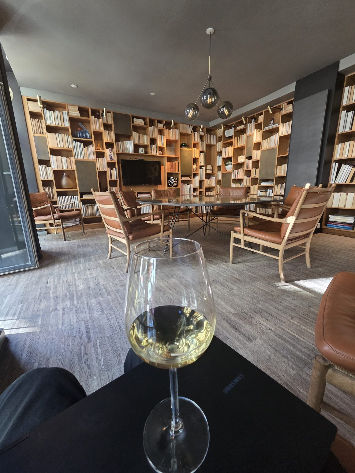 Glass of white wine in a stylish library lounge with floor-to-ceiling bookshelves.